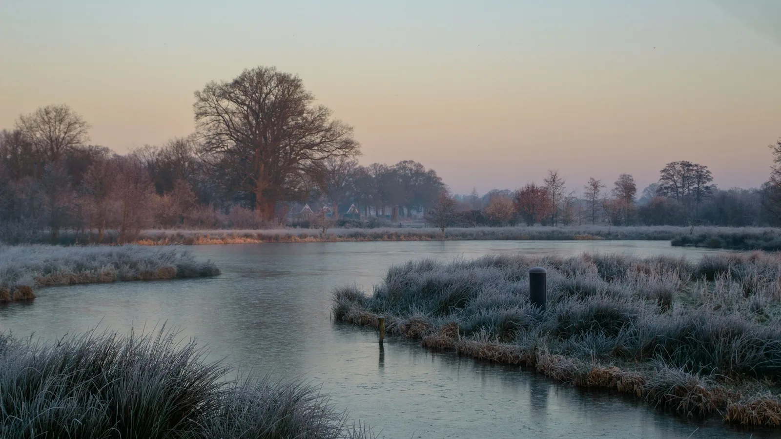 Berijpte polder met water in het eerste ochtendlicht